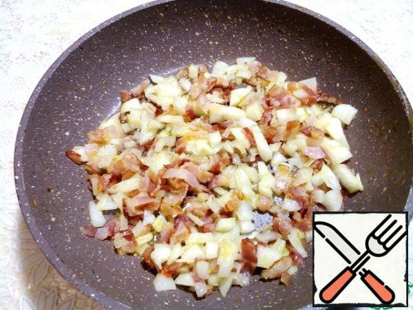 In the same pan, put the sliced half-smoked bacon, fry for a minute and add the chopped onion.
Fry everything together for two minutes on medium heat, stirring all the time.