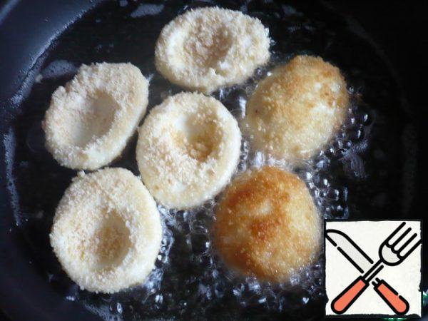 Turn on the pan and pour in the vegetable oil for deep-frying. Carefully spread the breaded proteins in a well-heated vegetable oil and fry. When the eggs are fried on one side, turn them over on the other. So fry all the eggs until Golden brown.
The eggs are crispy and beautiful.