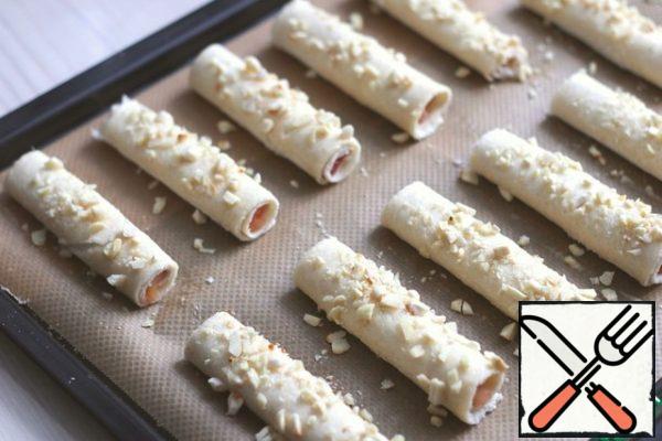 Grease the tubes with beaten egg and sprinkle with crushed and fried almonds. Send the baking sheet in a preheated t180-190C oven and tinted to the desired color.