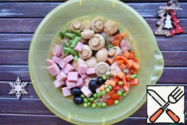 Add the selected vegetables to the minced meat: diced carrots and bell peppers, frozen green peas and string beans, mushrooms and whole olives. Add the ham cubes, salt and spices. Mix everything thoroughly.