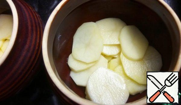 Peel the potatoes and cut them into thin slices.
Add salt and put it on the bottom of the pots, greased with vegetable oil.
