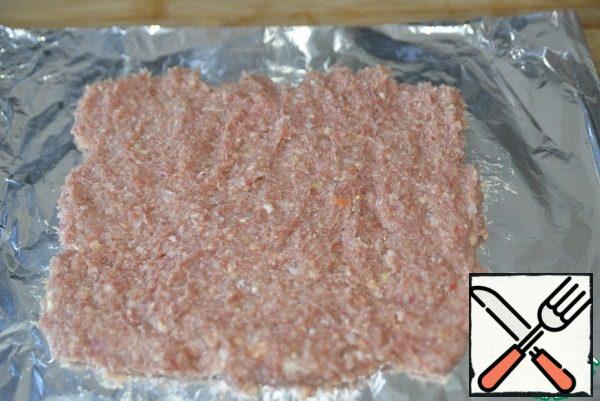 Take the foil, fold it in half, put a layer of minced meat on top with a thickness of about 1.5-2 cm, level it into a rectangle.