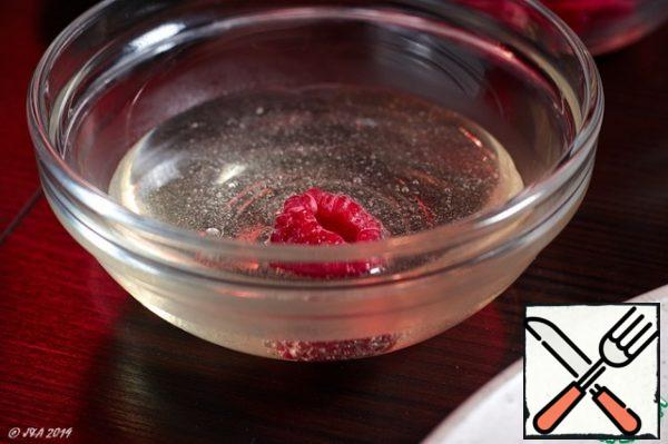 Let's start decorating. We dip frozen raspberries in a hot neutral glaze.
