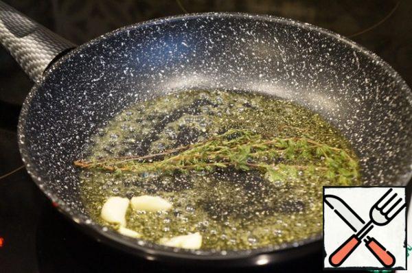 Add both types of oil to the pan. Press the garlic clove with the wide side of the knife, cut it into 2 parts, and throw it in the oil. Put the thyme. Fry for a few minutes over medium heat. Then discard the garlic and set aside the thyme.