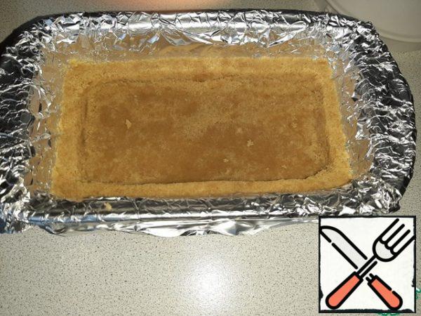 Cover the baking dish with foil so that the edges of the foil are equal to the height of the form. This is necessary so that the pastry can be easily removed together with the foil without damaging it. Flatten the cookie into shape, forming small sides at the edges. Dry in a preheated 180° oven for 5 minutes.