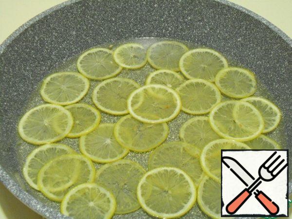 Prepare the syrup, lower the lemon rings and cook over medium heat for 20 minutes. The task is not to cook candied fruits, but to make the crust soft.
Flip it into a colander when the syrup drains, put it on a baking sheet, cover with a lid or a film, do not over-dry them.
