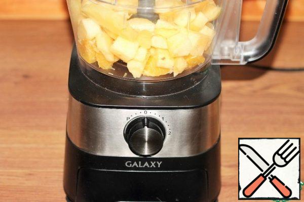 Put the fruits: apples, orange and pineapple in the bowl of a food processor.

