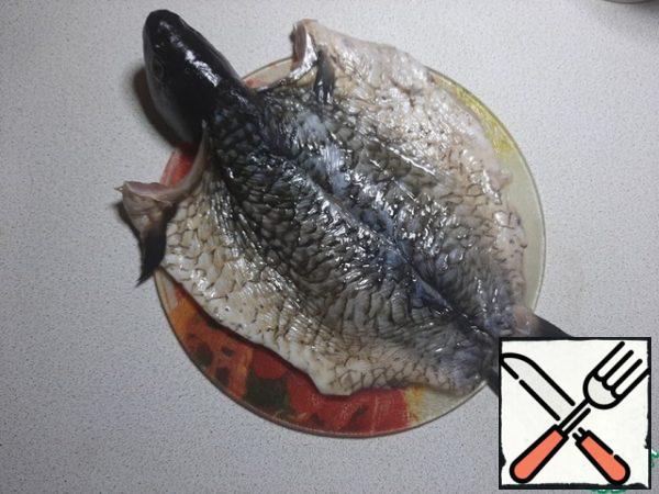 Clean the fish, remove the insides and gills. Make an incision along the ridge, not reaching the head. On the abdomen, also make an incision to the end on both sides. Remove large bones and spine. You can do this with scissors or by cutting with a knife and pulling out each bone, and then carefully remove the ridge.
