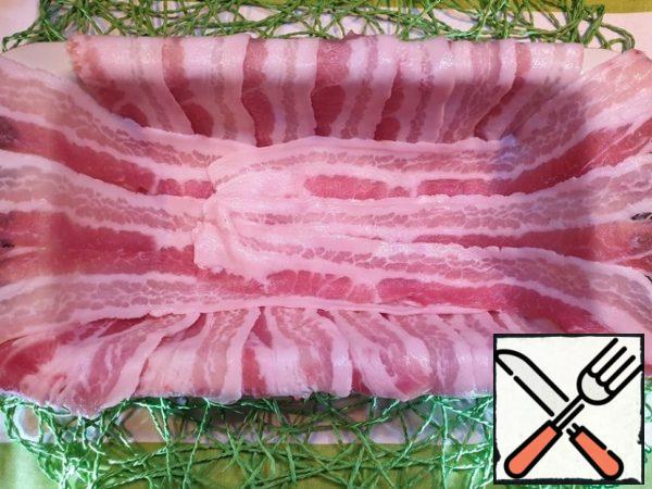 A suitable baking dish is spread with bacon so that its edges hang down.
I took raw pork bacon, you can use smoked or boiled-smoked. But keep in mind that the carbonate and cheese are quite salty. Therefore, be careful with salt.