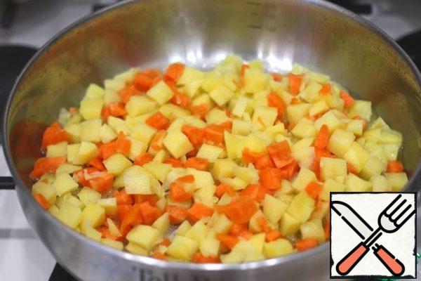 Add 5 tablespoons of vegetable oil to the pan. Heat the pan over medium heat. Next, put the cubes of potatoes and carrots. Fry the potatoes and carrots over medium heat for 3-5 minutes.