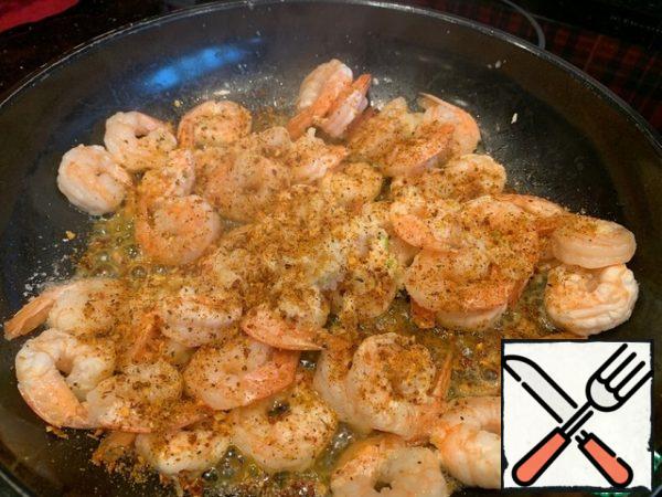 As soon as the shrimps are thawed and give the liquid drain it, add to the shrimps olive oil, garlic squeezed out by a press and spices.
