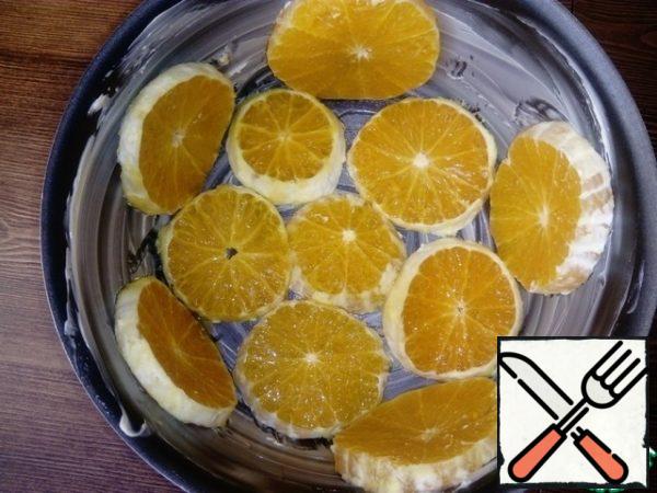 The bottom of the baking dish is greased with butter and spread the orange circles. The diameter of the mold is 18 cm.