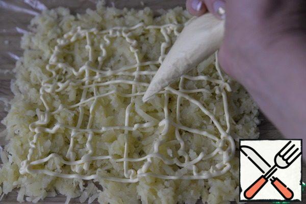 Put the bag on a large Board. Peel the potatoes and grate them on a film in the shape of a rectangle. Apply a mayonnaise mesh to the potatoes. For ease of application, put the mayonnaise in a cooking bag (package).
