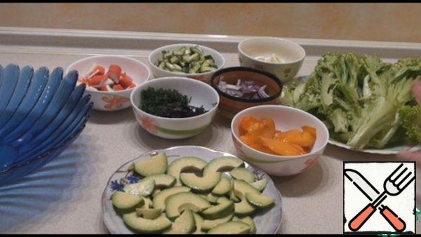 Peel the pitted avocado, cut it across in half rings, sprinkle with lemon juice and salt. Cut the persimmon in half and cut into slices. Cut the cucumber across, cut both parts into long strips. Cut the onion into half rings. Peel the quail eggs and cut each one in half lengthwise. cut the crab sticks into slices about 2 cm thick.

