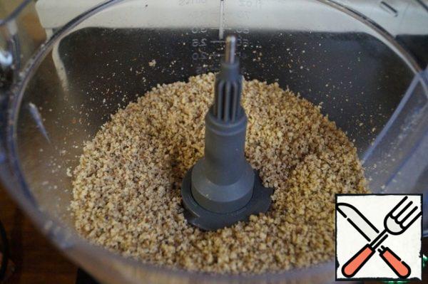 Load the walnuts into the bowl of the combine and grind them into fine crumbs.