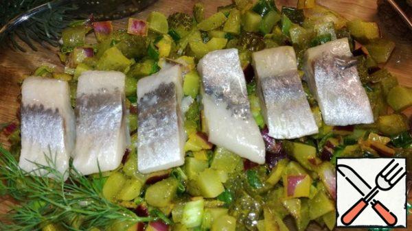 Cut the herring fillet into pieces and put it on top of the salad. Decorate according to your taste.