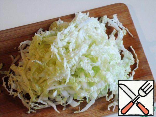 If the Peking cabbage has wide leaves, cut them in half lengthwise at first, then cut them into strips 5-7 mm wide.