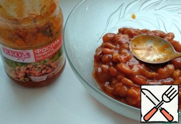 In a salad bowl, transfer the bottom of the jar with baked beans in Serbian.
