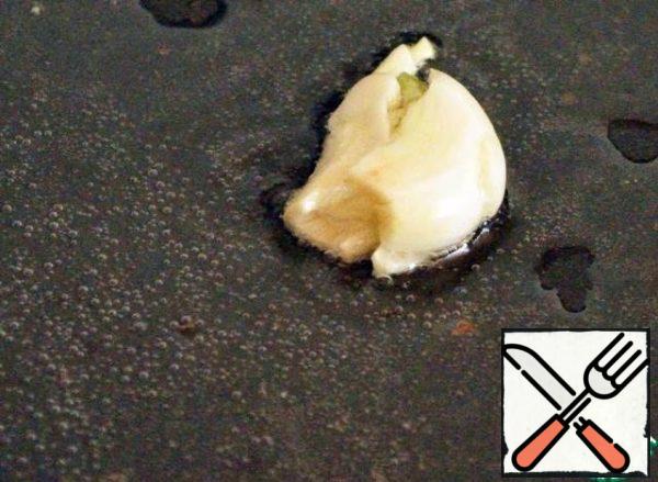 Peel the garlic clove and crush it with the wide part of the knife blade. Send in a heated pan with a small amount of oil, so that the garlic gave the oil all its flavors. Fry it, turning it periodically, until Golden brown and throw it away.