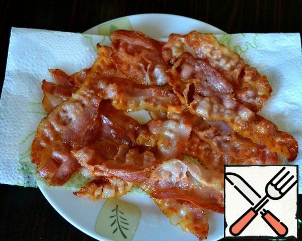 Sliced thin (!) strips of bacon fry in a dry pan on both sides, so that it is fried. Put the finished strips of bacon on a paper towel to remove excess fat.