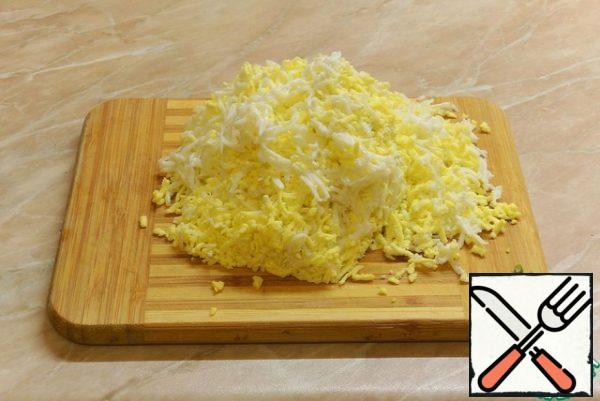 Boil the eggs and grate them on a fine grater.