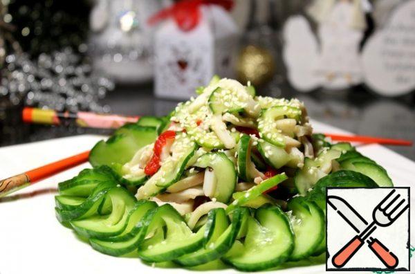 Get squid with vegetables, squeeze. Cucumber, cut into a garland, slightly squeeze, put on a dish ring, pour a little soy sauce, put in the middle of the squid with vegetables. Sprinkle with roasted sesame seeds.