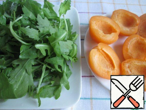Wash the apricots, cut them in half and remove the seeds. Wash the arugula and dry it on a napkin.