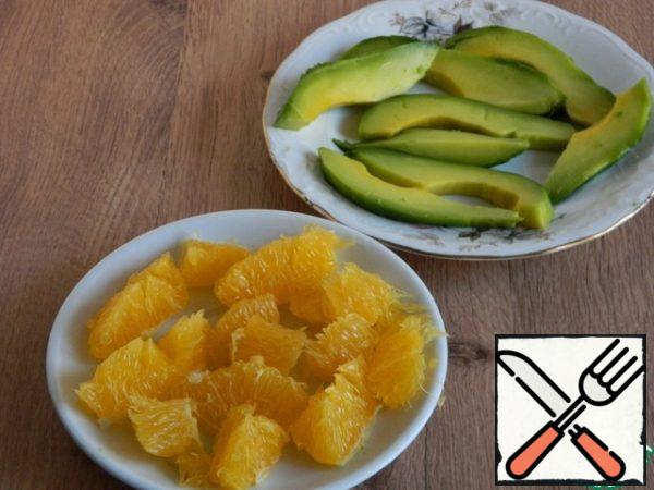 Cut the avocado into thin slices. Divide the orange into slices and peel from the films, cut into pieces.
