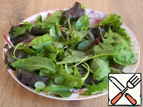 Put a mix of salad leaves (chard, arugula, lettuce, frisse) on a plate.