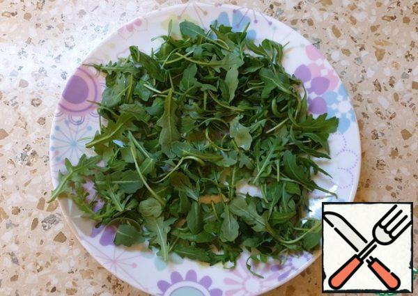 Collecting salad. Put arugula on a plate.