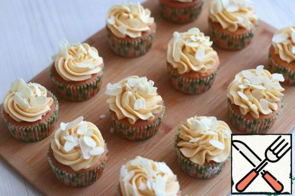 Apply the prepared cream to the cupcakes using a pastry bag. Sprinkle the cupcakes with almond petals.