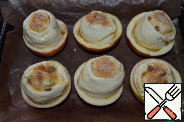 Roll cut into 6 identical parts, put in Apple cups, cover with film. Leave for proofing, 20-25 minutes, in a warm place.
Before baking, grease the blanks with a mixture of milk and yolk, sprinkle with brown sugar.
