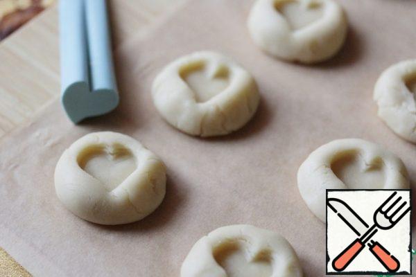Then roll the dough balls (20 pieces), put them on a parchment-covered baking sheet.
Make indentations in each ball using a special device (or the handle of an old opener, or just a finger), remove the sheet in the refrigerator for 1 hour.