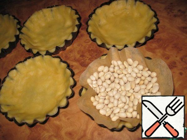 Divide the dough into 6 equal parts and place it in tartlets. Press the dough tightly so that it covers the bottom and sides well. To keep the tartlets in shape during the baking process, fill the dough molds with beans. Bake in the oven, preheated to 200 degrees, until Golden. My electric oven took 25 minutes.