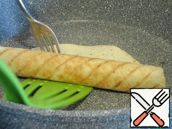 When the mass is slightly baked , it will become matte,
using a spatula and fork, roll half of the tortilla into a roll.