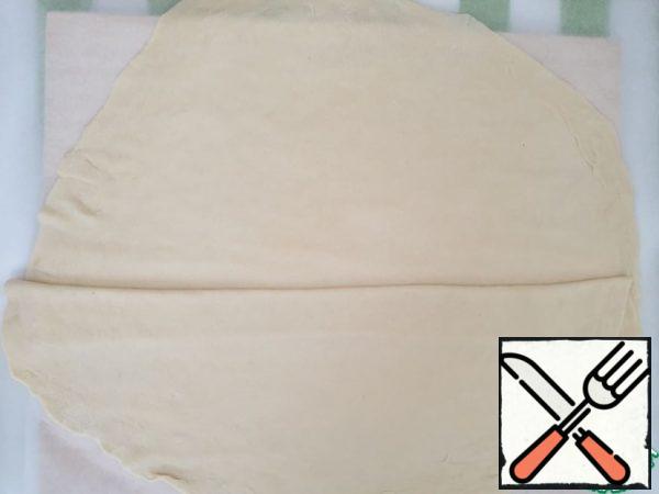 While working with the dough, we sprinkle the work surface with flour.
Take 1 blank, roll it out, then just gently mash it with your hands. The dough turns out to be very pliable and stretches well.
The thickness will turn out like a sheet of paper.