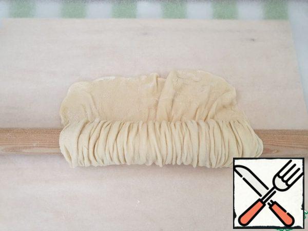 A little dust the dough with flour. Wind it on a rolling pin, leaving 2 cm of the edge free and slightly squeeze the edges to get an accordion.