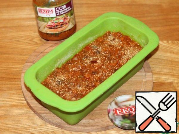 Spread the eggplant honeycomb evenly on top. With the back of a large spoon, draw 3 deep strips. The vegetable juice from the sauté will penetrate the meat pudding and soak it. Sprinkle with breadcrumbs (1-2 tbsp).