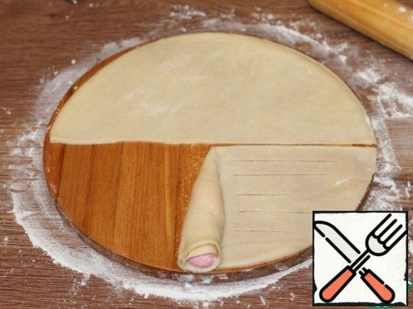Roll the filling with the dough to the middle of the semicircle and cut the strips in the second part of the semicircle.