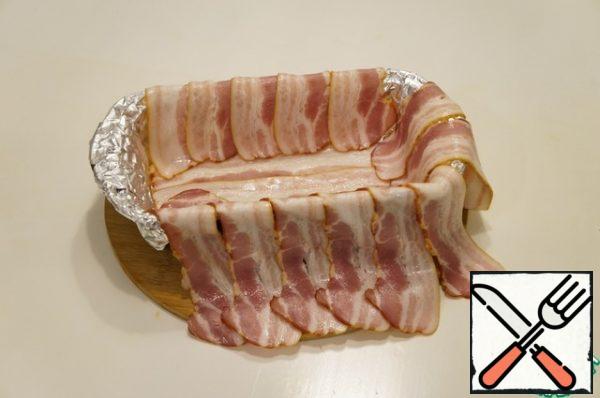 Cover the cupcake mold with foil and lay out the strips of bacon.