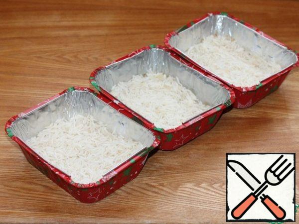 Turn on the oven for 180* C. in the baking molds, spread the rice evenly.