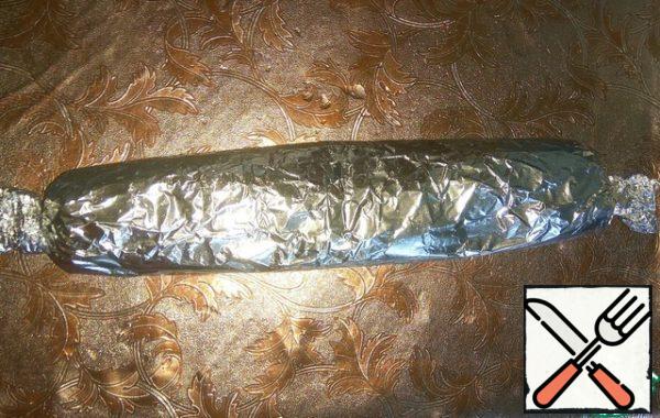 Grease the foil with oil. Lay out the roll. Wrap tightly. Then take another foil and roll the second layer, twisting the edges like candy.