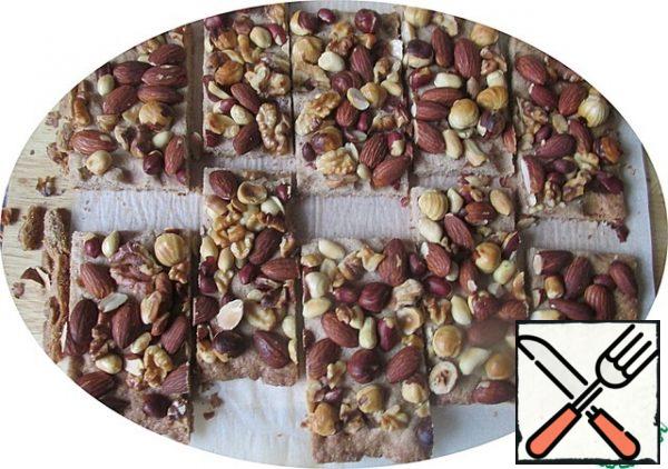 Send it to the oven and bake for 25-35 minutes. The nuts should be noticeably browned. Remove from the oven, put together with the parchment on a Board, cool for 10 minutes and cut with a sharp thin knife into 10 rectangles.