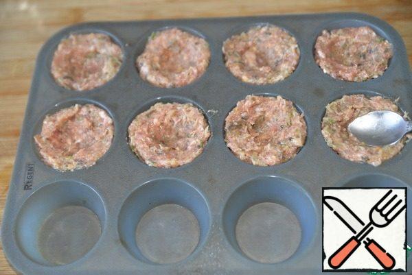 We take molds for cupcakes (muffins), I have silicone. Spoon the minced meat into the molds. Make a recess with your fingers or a teaspoon.
Place the molds in a preheated 200 degree oven and bake until cooked for 30 minutes.