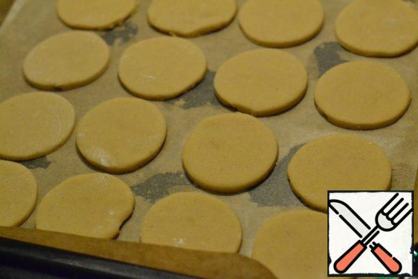 The cutting Board is well sprinkled with flour.
Roll out half of the dough 5 mm high.
Cut out the circles with a mold or a Cup, and put the diameter At your discretion on the prepared baking sheet (spread with baking paper).