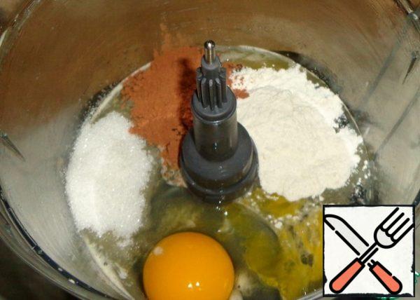 Now you need to make a cream. In the bowl of the combine, break one egg, pour sugar, cocoa and flour.