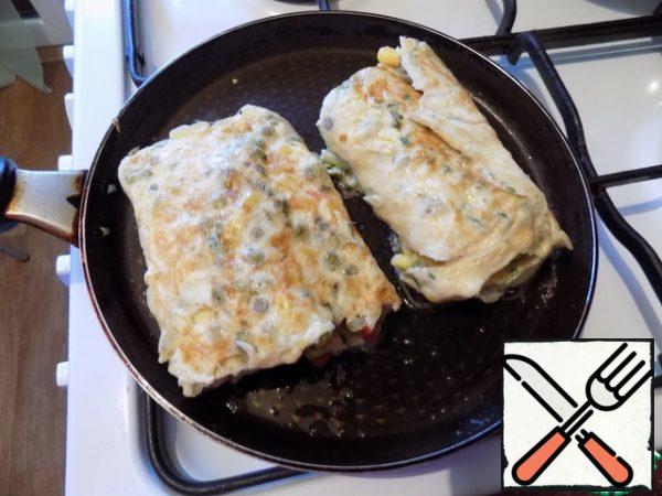 When it was completely twisted, I cut it in half for convenience. So it is more convenient to finish it until it is ready. Reduce the heat to a minimum, cover and fry the omelet to a beautiful color on both sides, turning it over a couple of times.