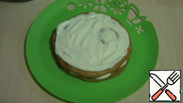 Put a little sour cream on the dish so that the cake does not move out. The first 2 cakes are smeared with sour cream.