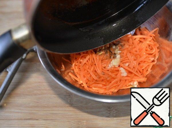 Squeeze the garlic into the carrots, add the ground coriander, chili flakes. Heat the oil to a light haze and pour it on the carrots, mix.