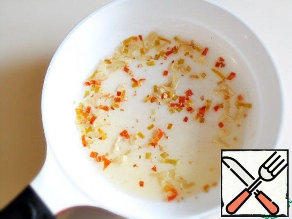 Cut the garlic into small plates and finely chop the hot pepper. Lightly fry the garlic and pepper over medium heat, in a small amount of vegetable oil.
Thanks to this treatment, they will get a brighter flavor and give the oil its own taste.